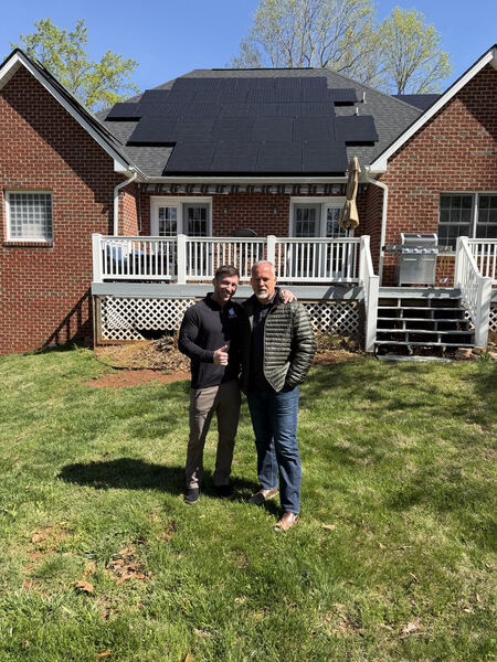 Solar consultant and homeowner giving thumbs up in front of completed solar installation